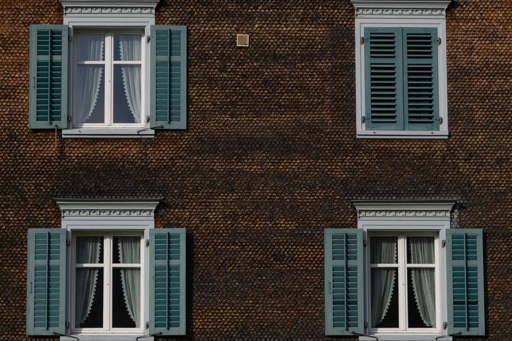 Façade de brique rouge aux volets gris-vert et encadrements de pierre
