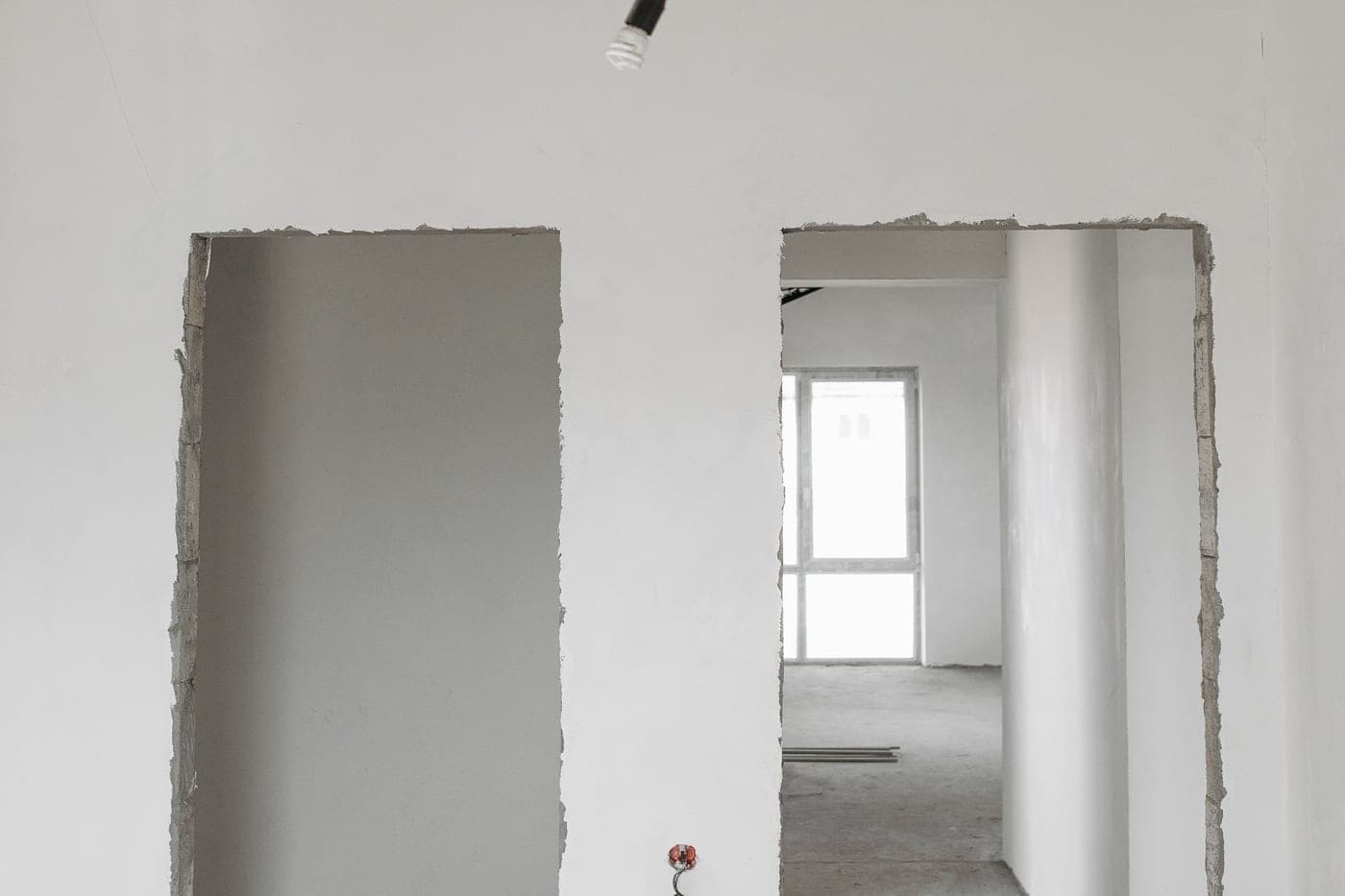 Deux ouvertures brutes dans un mur enduit d'un logement en chantier