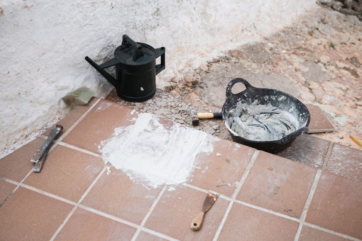 Carrelage extérieur en terre cuite en cours de pose, mortier, truelle et seau sur la terrasse