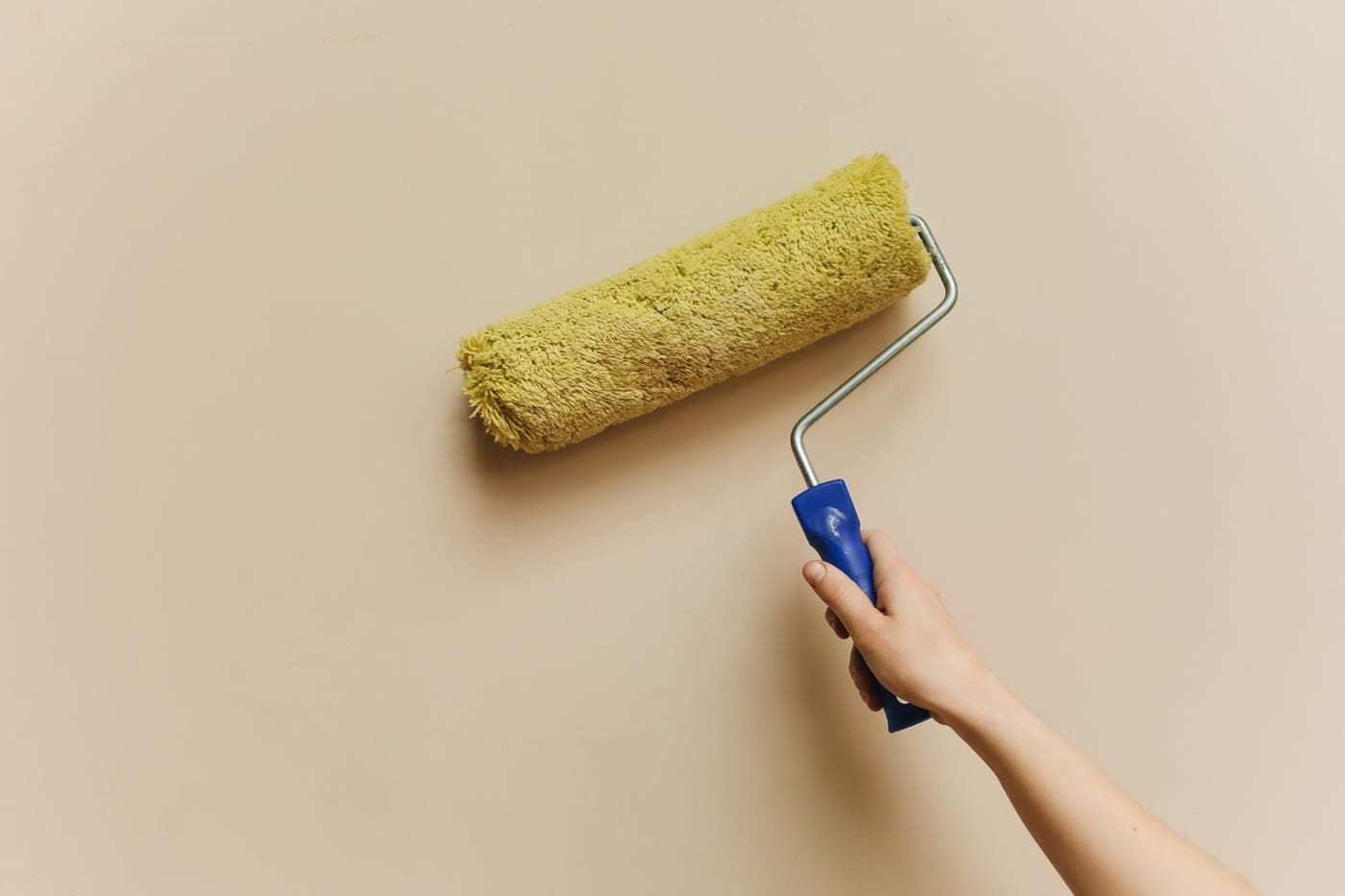 Rouleau à peinture jaune passé sur un mur beige